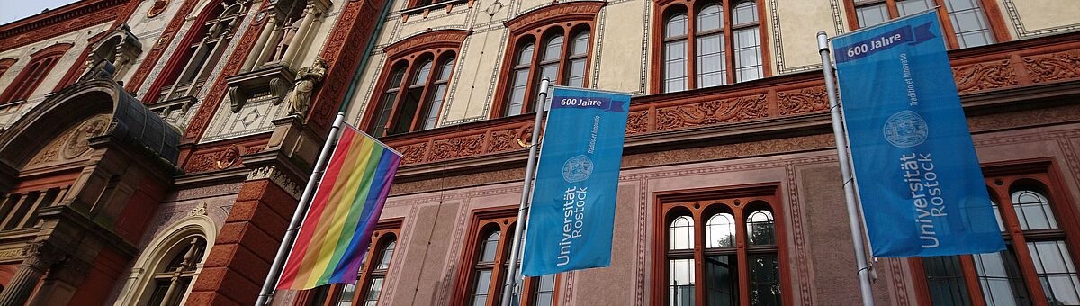 [Translate to English:] Regenbogenflagge vor dem Universitätshauptgebäude.