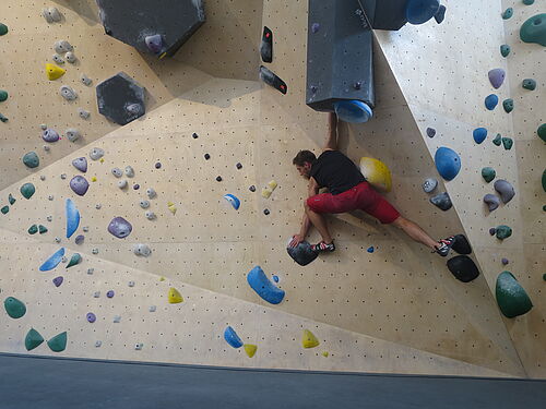 Tim Völzer  in der Rostocker Boulderhalle „45 Grad“.  Die Route, die der 27-Jährige dort klettert, besteht aus den schwarzen Steinen und geht nach links oben. Foto: privat