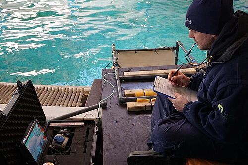 Tim Hüttner während einer Versuchssitzung während er den Delphin über eine Unterwasserkamera beobachtet.