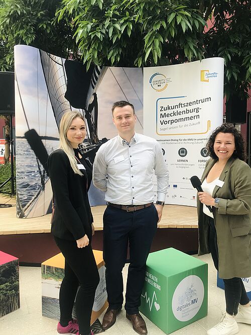 v.l.: Josephine Rößler, Leon Griesch, Saskia Paetsch vom Zukunftszentrum Mecklenburg-Vorpommern auf der Ausstellungsfläche im Atrium, Konrad-Zuse-Haus in Rostock. (Foto: Zukunftszentrum Mecklenburg-Vorpommern